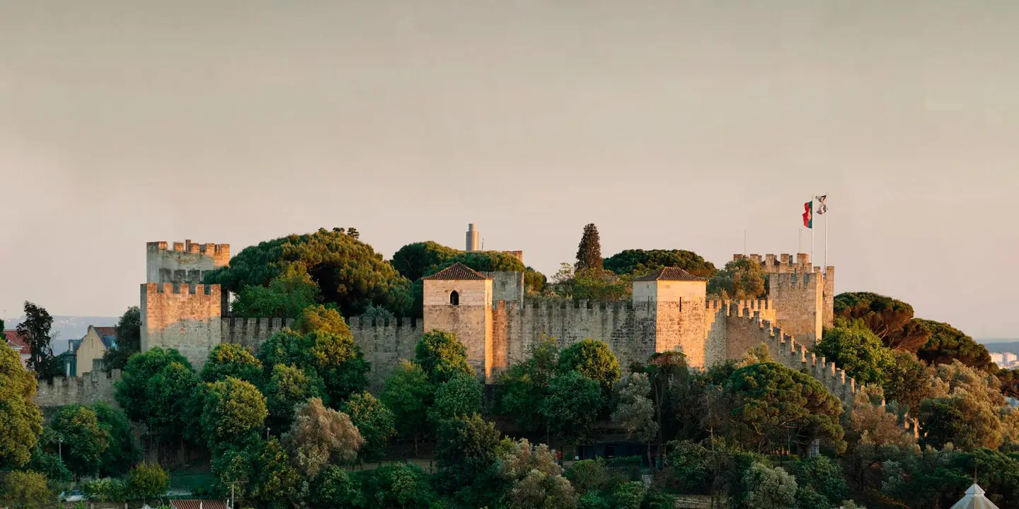 Les remparts et les tours du château de São Jorge au-dessus des arbres, sur la colline qui domine Lisbonne